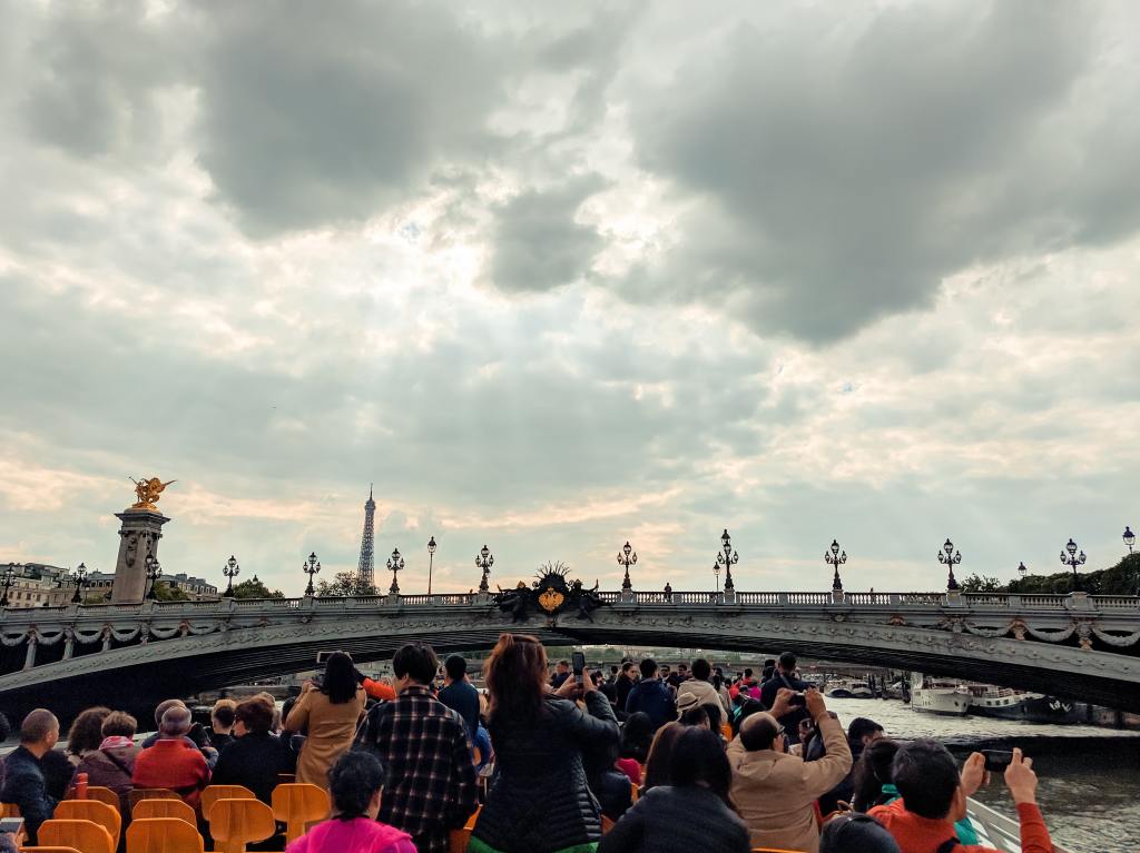 Gens sur une croisière sur la Seine qui visitent Paris en prenant des Photos avec Voilà Tours